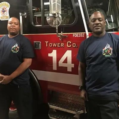 Two men standing in front of a fire truck.