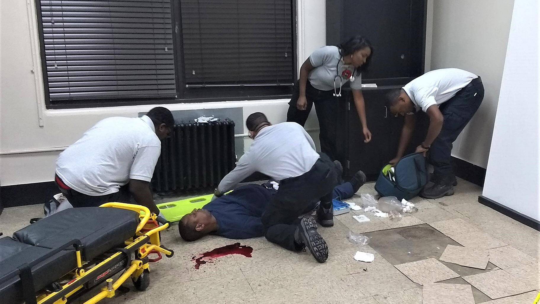A group of men standing around an injured person.