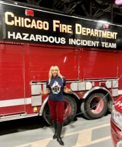 A woman standing in front of an emergency vehicle.