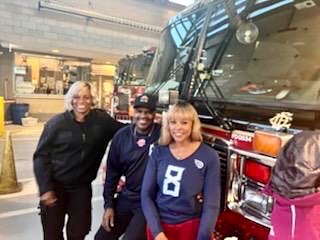 Three people standing in front of a fire truck.