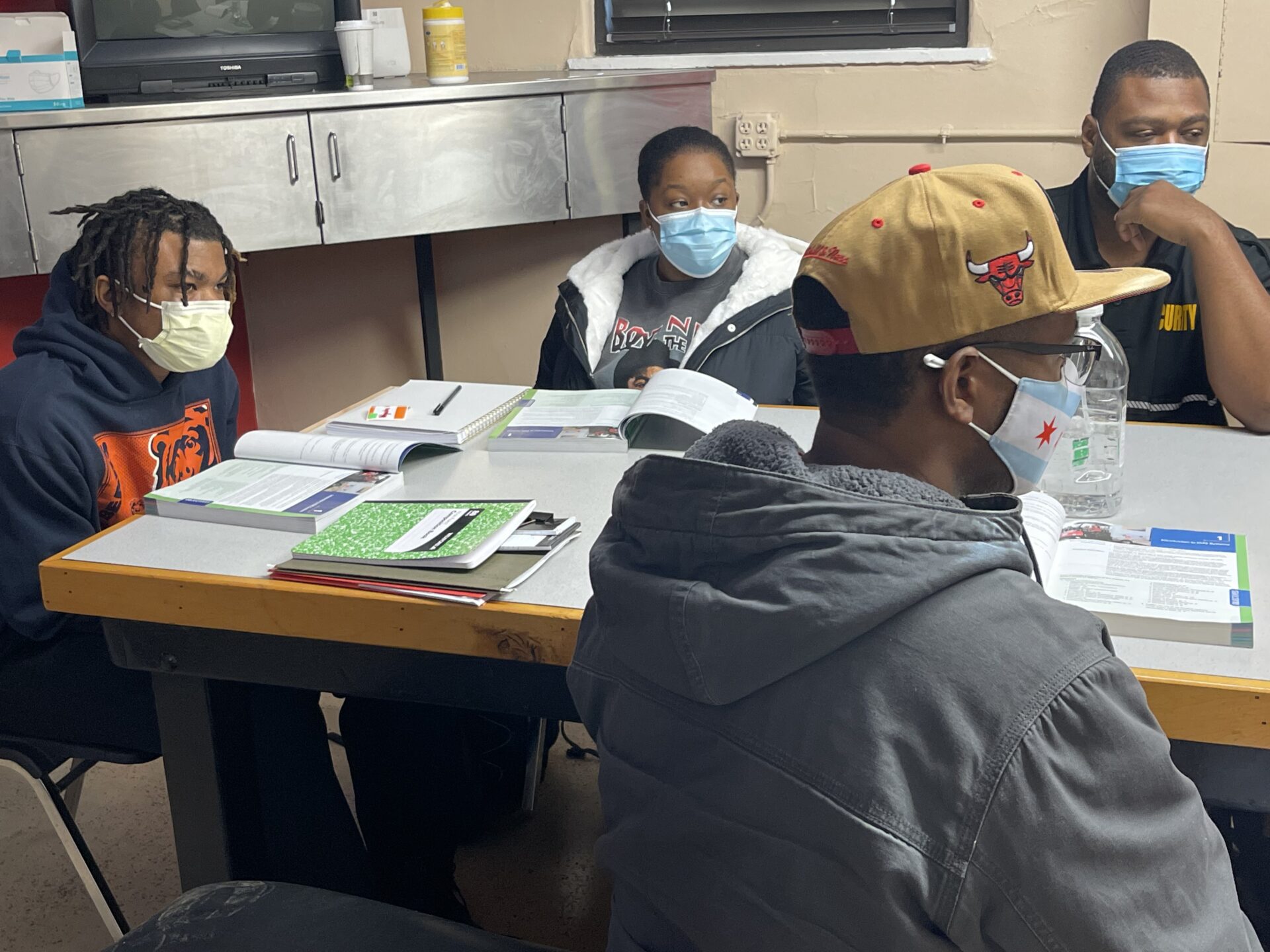A group of people sitting at a table with masks on.